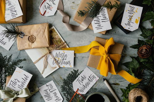 Handwritten tags with Merry Christmas written in several different languages and presents photo