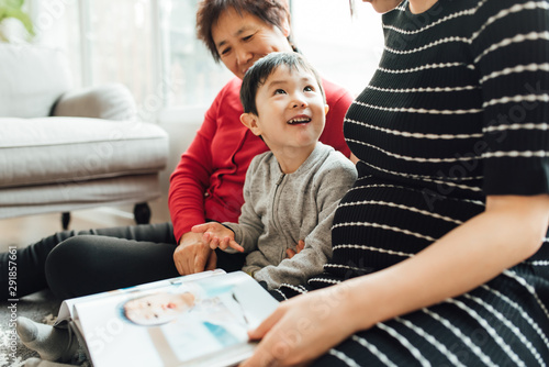 Grandmother,pregnant daughter and grandson watching album together at home photo