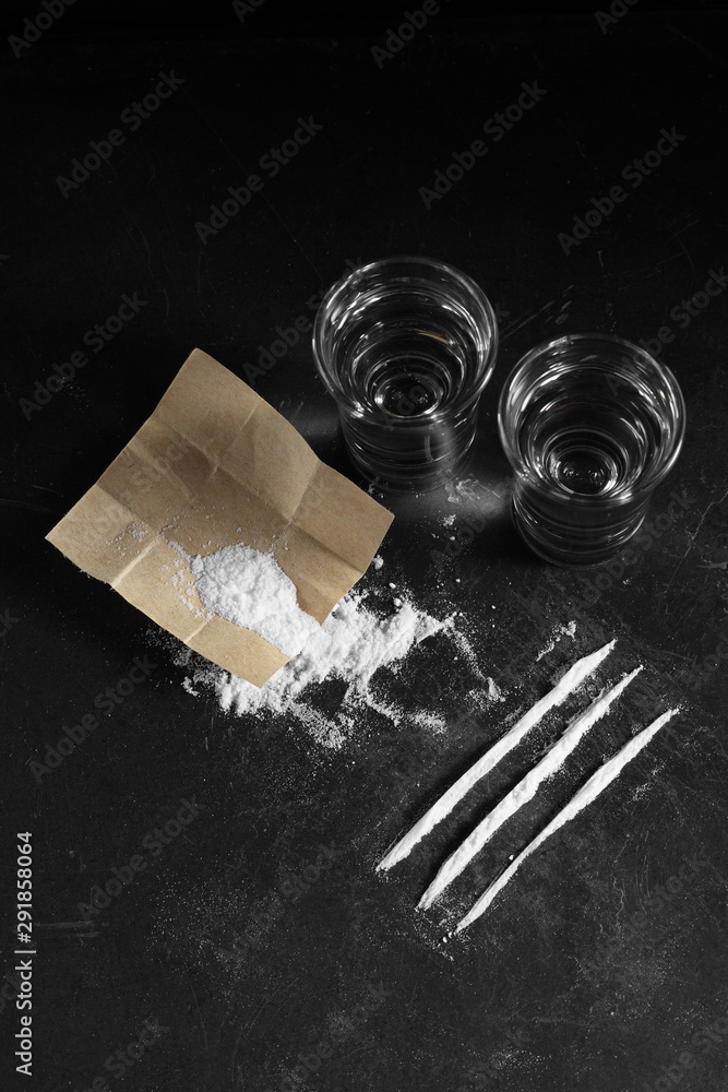 close up pile of cocaine in paper and vodka on black background