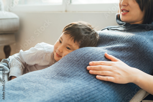 Young pregnant mother with son at home