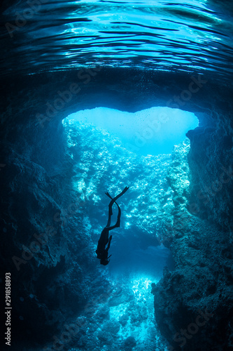 Female free diver underwater in the heart shape cavern with back light photo