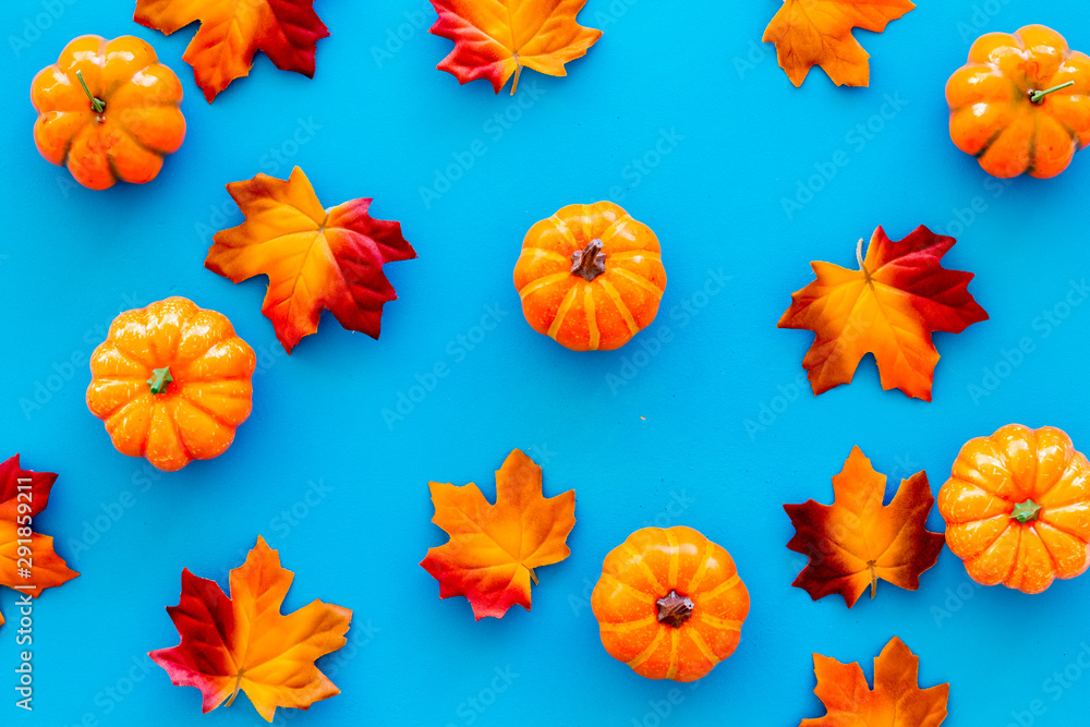 Autumn composition. Pattern with red and orange leaves and pumpkins on blue background top view