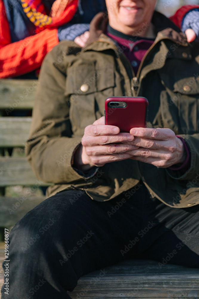 Close up of a man's hands as a mature couple in their sixties using a mobile phone. Close up of a man's hands as a mature couple in their sixties using a mobile phone.