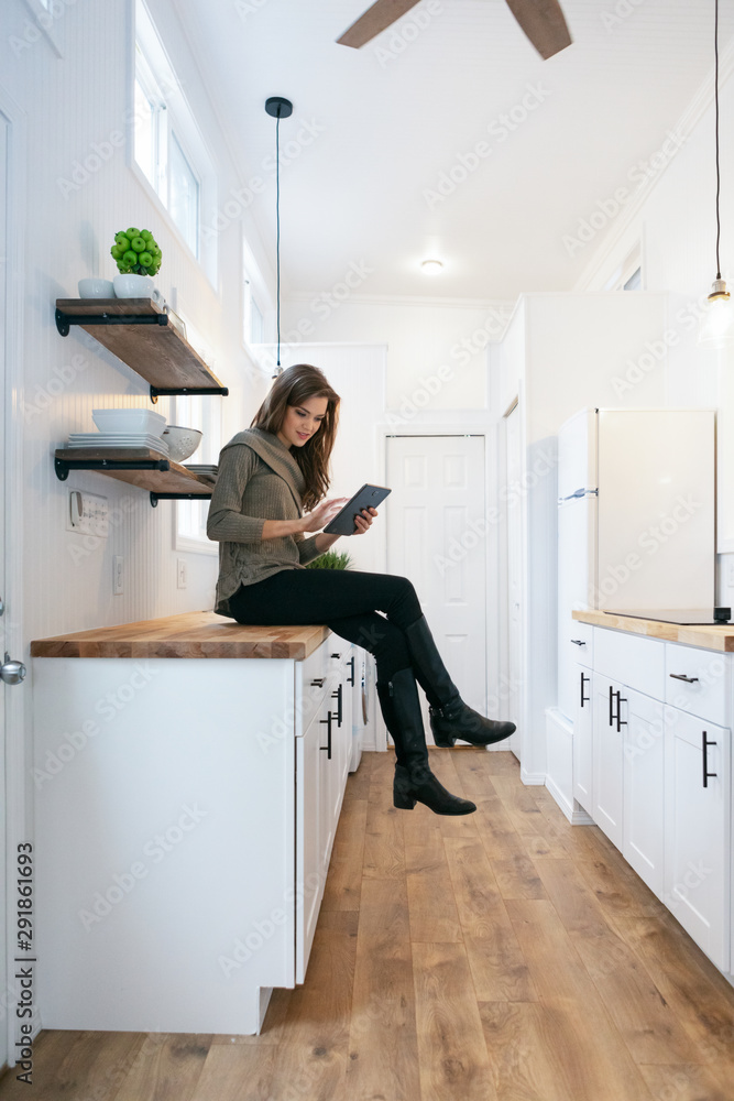 Home: Woman Sits On Counter Checking Digital Tablet Home: Woman Sits On Counter Checking Digital Tablet
