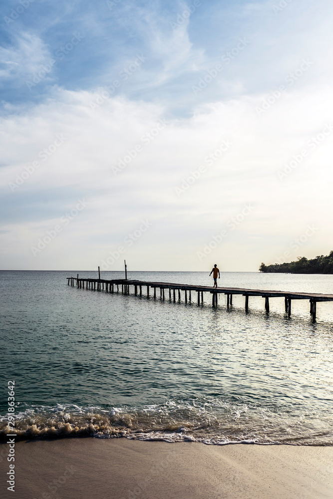Unrecognizable man walking on pier in amazing beach Unrecognizable man walking on pier in amazing beach