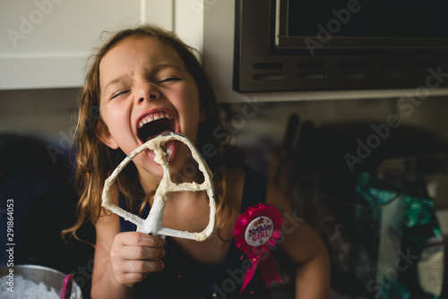 Girl licking beater at home photo