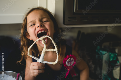 Girl licking beater at home