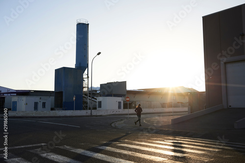 Female runner training industrial zone sunrise. photo