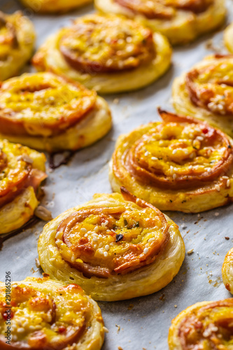 Rolls of puff pastry with ham bacon cheese sesame on baking tray