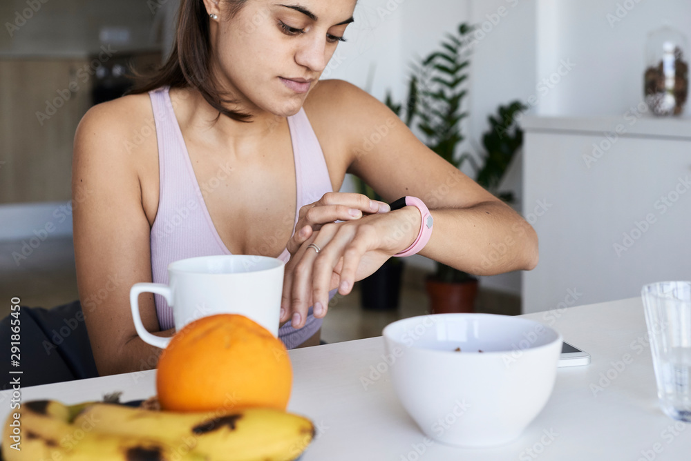 Sportswoman having breakfast checking smartband. Sportswoman having breakfast checking smartband.