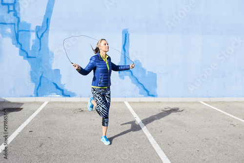 Aged fitness woman using skipping rope.