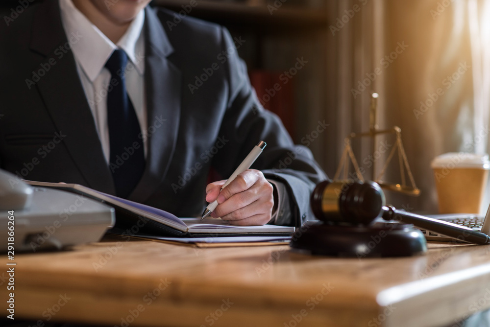 Lawyer working on a documents in courtroom with gavel and scales of justice, concepts of law. Lawyer working on a documents in courtroom with gavel and scales of justice, concepts of law.