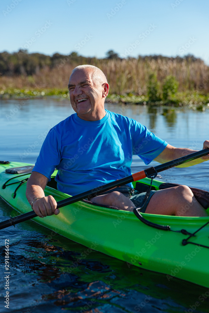 Active senior man in his seventies laughing while kayaking on a lake. Active senior man in his seventies laughing while kayaking on a lake.