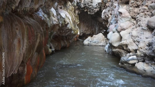 A river flowing inside an erosional cave and mineral formations on the walls