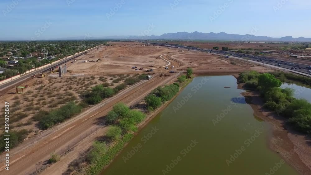 aerial shot flying over a pond to a construction project in the desert with a very busy freeway off to the right aerial shot flying over a pond to a construction project in the desert with a very busy freeway off to the right