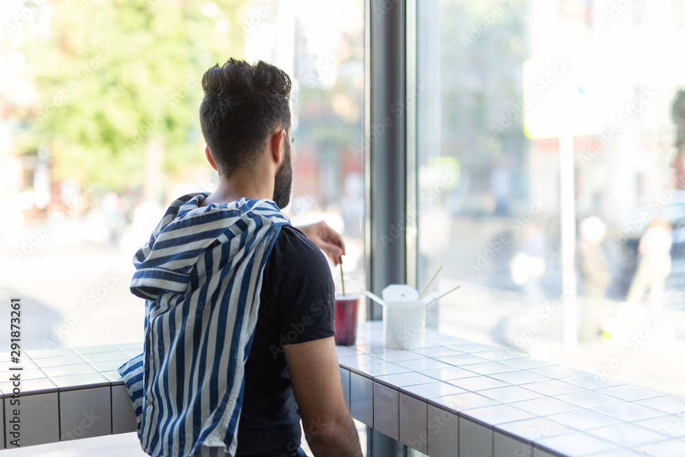 Positive young stylish guy drinking juice in a cafe during a break at work. The concept of rest and healthy snack. Positive young stylish guy drinking juice in a cafe during a break at work. The concept of rest and healthy snack.