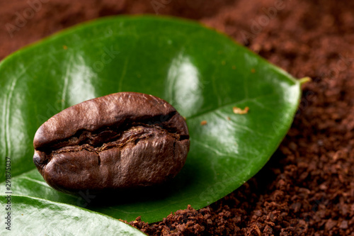 coffee bean with green leaf on ground coffee. concept: freshness of coffee beans, coffee with spices. close up
