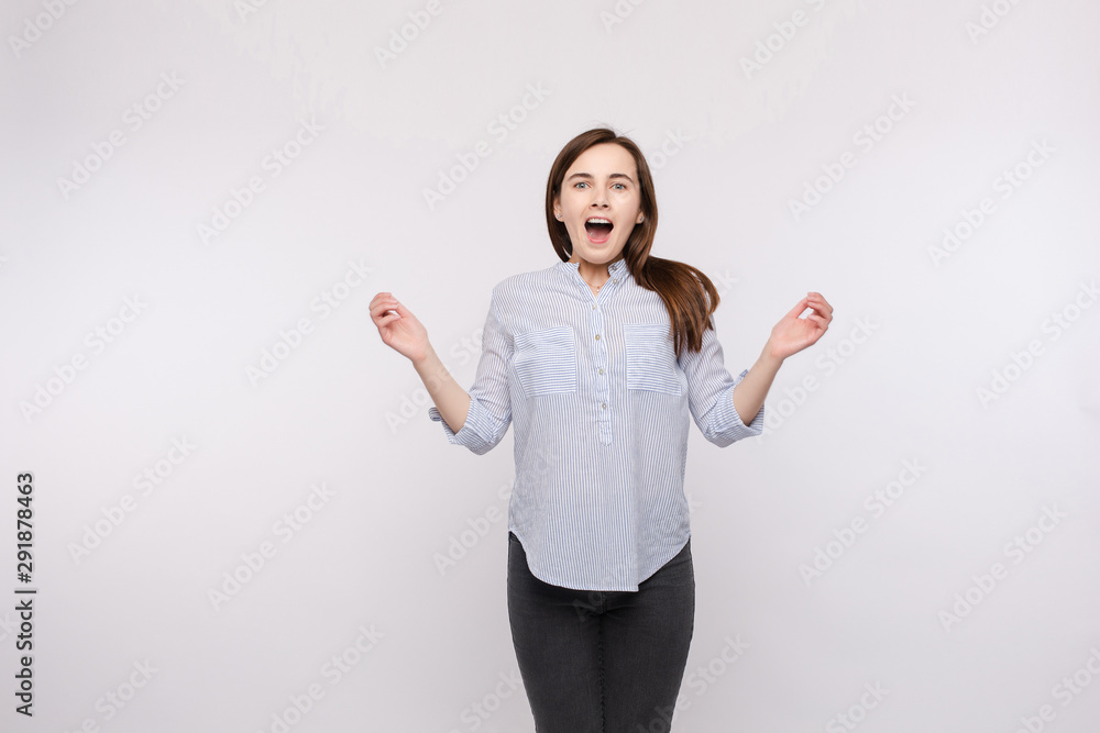 Studio portrait of a young girl with brunette hair wearing casual clothes jumping because of surprise. Astonished happy woman jumping in the air. Winning concept. Happiness. Studio portrait of a young girl with brunette hair wearing casual clothes jumping because of surprise. Astonished happy woman jumping in the air. Winning concept. Happiness.