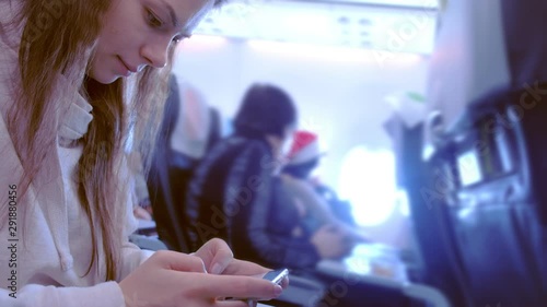 Woman playing a game on a mobile phone while flying a plane. Passengers on Board the aircraft