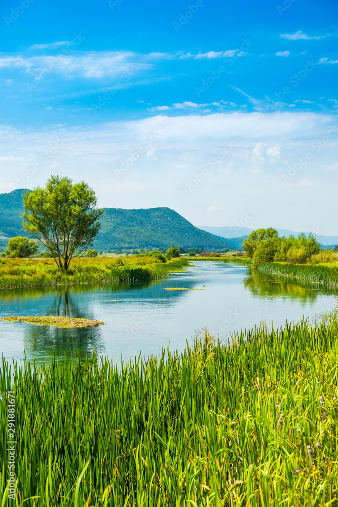 Beautiful nature landscape, Gacka river among grass banks, Lika region of Croatia Beautiful nature landscape, Gacka river among grass banks, Lika region of Croatia
