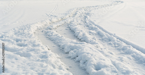 Car tire tracks on winter snow field