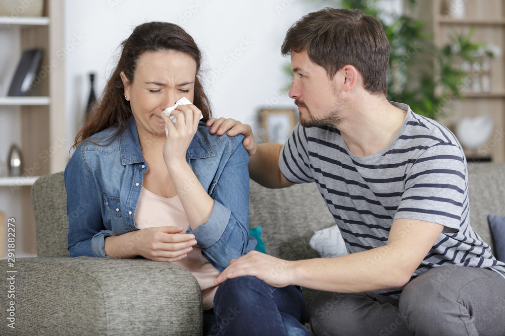 young woman weeping being conforted by husband young woman weeping being conforted by husband