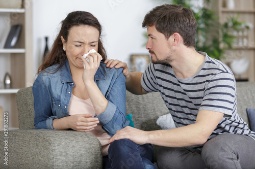 young woman weeping being conforted by husband