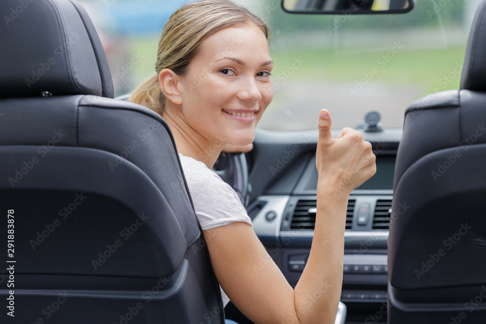 beautiful smiling girl in car with thumbs up