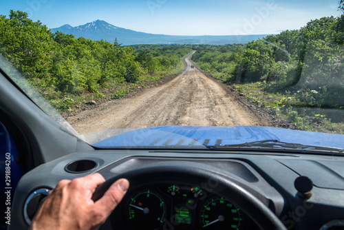 View from behind the wheel of a car on a dirt road in the middle of the expanse stretching into the distance.