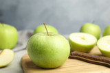 Fresh ripe green apple on wooden board against blue background, space for text