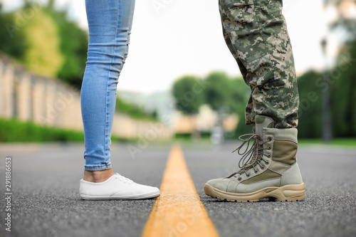 Man in military uniform and young woman separated by yellow line on road, closeup