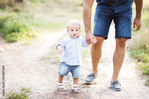 Young father walks with his cute little boy in a forest. Father's Day