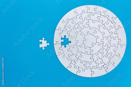 Fotografie Unfinished white jigsaw puzzle pieces on blue background, The last jigsaw puzzle of success