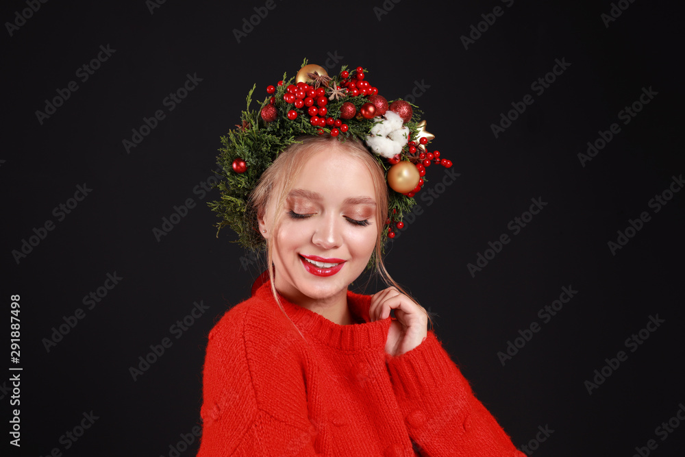 Beautiful young woman wearing Christmas wreath on black background Beautiful young woman wearing Christmas wreath on black background