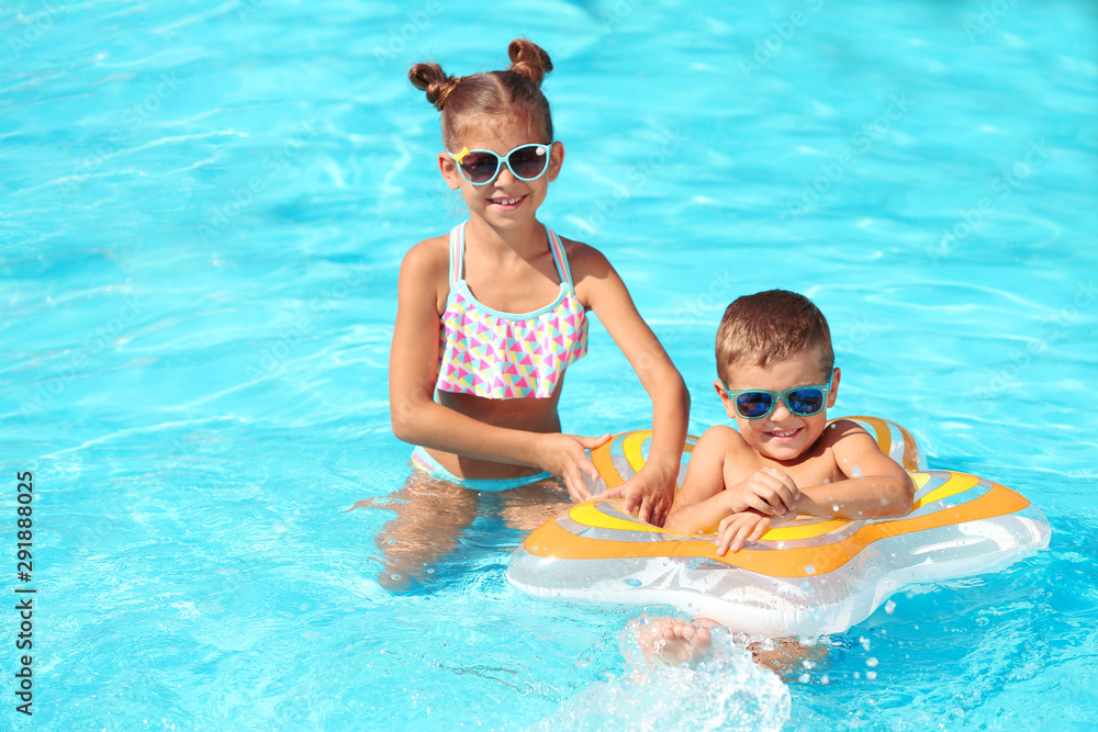 Cute little children with inflatable ring in swimming pool