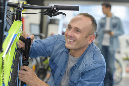 smiling mechanic working on bicycle shock absorbers