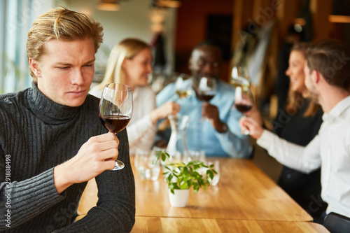 Junger Mann bei einer Weinprobe oder Verkostung photo