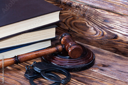 Handcuffs and a wooden gavel in front of manila folders.