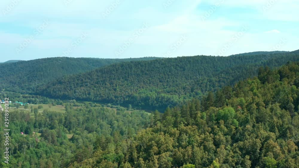 The drone flies through the mountain towards the river valley. Ahead is a mountain range with dense forest. Sunny day. The drone flies through the mountain towards the river valley. Ahead is a mountain range with dense forest. Sunny day.