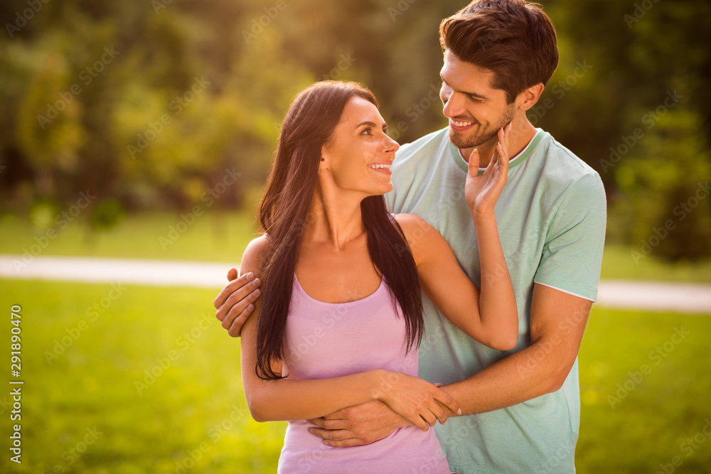 Fototapeta premium Portrait of lovely married two people piggyback wearing bright t-shirt outside in park