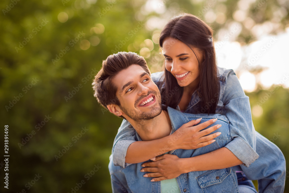 Close up photo of lovely sweethearts looking piggyback wearing denim jeans jackets outdoors Close up photo of lovely sweethearts looking piggyback wearing denim jeans jackets outdoors