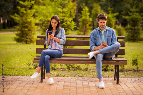 His he her she nice attractive lovely focused concentrated best friends wearing denim spending free spare time leisure sitting on bench browsing in green wood forest outdoors