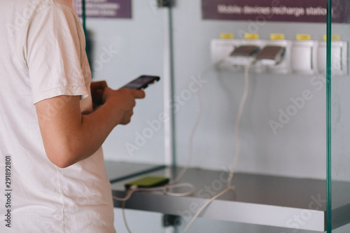 Young man connect his mobile phone to charger and typing message on phone photo