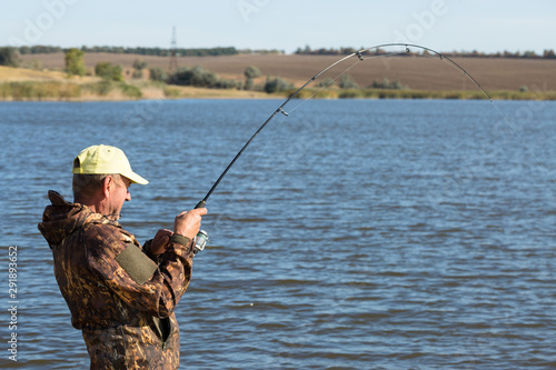 A man catches fish on a spinning rod on a larva. A fisherman is fishing in a pond.