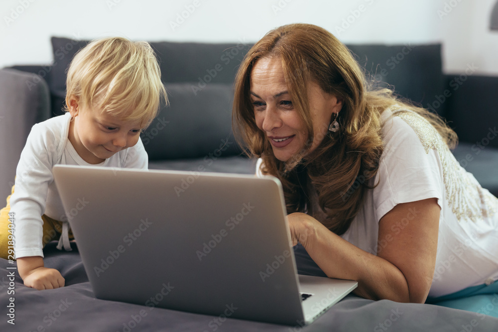 woman with her grandson using laptop computer at home