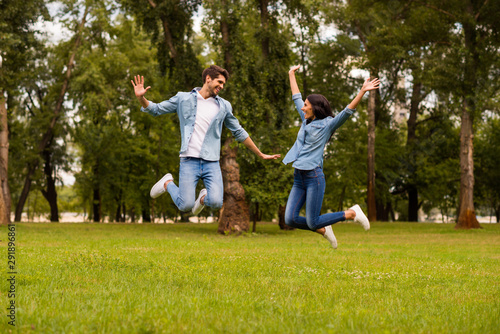 Full size photo of overjoyed pair jumping high in green park best weekend ever wear denim outfit