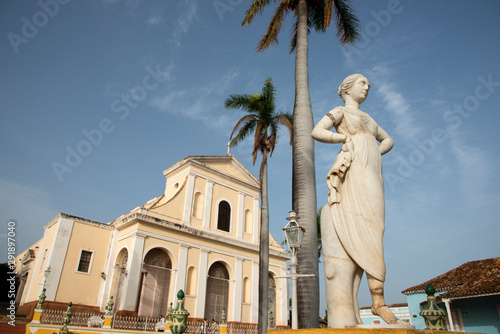 Statue in Plaza Mayor, Church of the Holy Trinity (Iglesia de la Santisima Trinidad) in the background, Trinidad, Cuba photo
