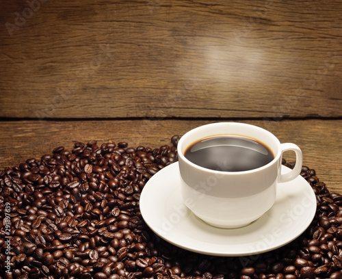 Warm cup of coffee and beans on old wooden background