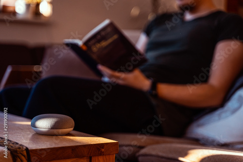 Smart ai speaker. Smart home concept with man reading in the background © David Ferencik