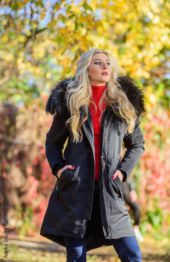 Girl in warm coat stand in park nature background defocused. Create fall outfit to feel comfortable and pretty. Woman long blonde hair wear stylish outfit with parka. Modern outfit for youth